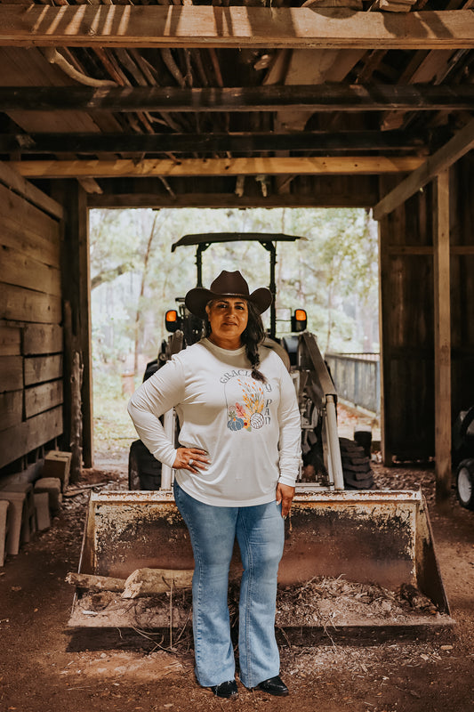 Woman in a barn wearing our gracias y pan long sleeve tee