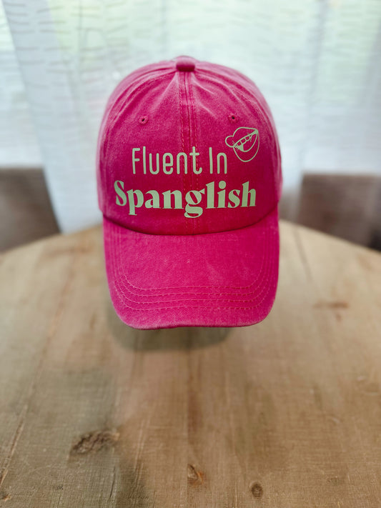 Hot Pink Dad Hat With Green Letters Saying " Fluent In Spanglish" . 