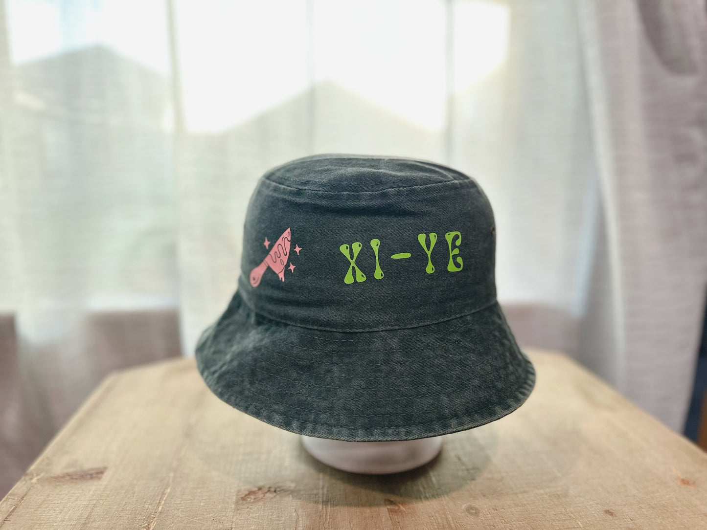 Denim Bucket Hat With Xi-Ye Branding In Green With a Pink Knife With Hearts And Stars. 