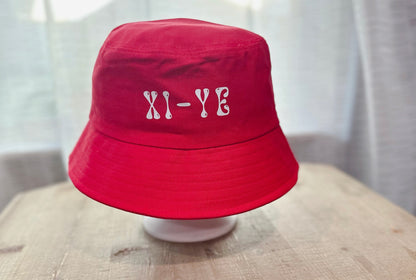 Xi-Ye Branding In White Text On Red Bucket Hat. 